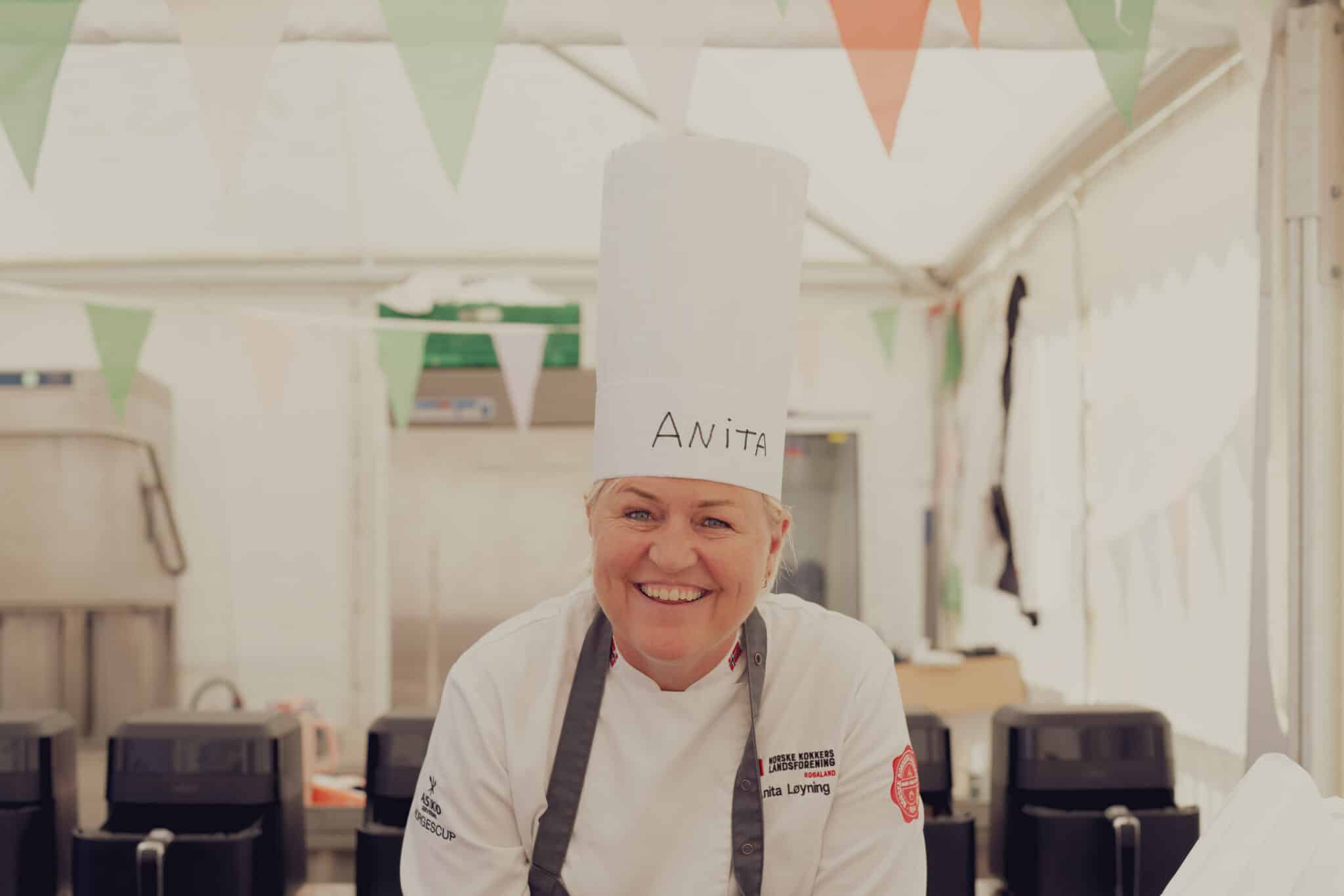 Anita Løyning står med kokkehatt og smiler under Gladmatfestivalen.